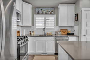 Kitchen with backsplash, white cabinetry, sink, and appliances with stainless steel finishes