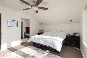 Bedroom with light carpet, connected bathroom, ceiling fan, and lofted ceiling