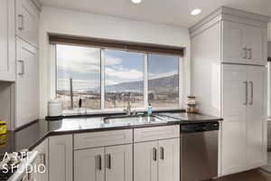 Kitchen featuring white cabinetry, dishwasher, sink, a mountain view, and dark stone counters