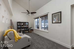 Living area featuring dark colored carpet, ceiling fan, and high vaulted ceiling