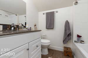 Full bathroom with tile patterned floors, vanity, tiled shower / bath combo, and toilet