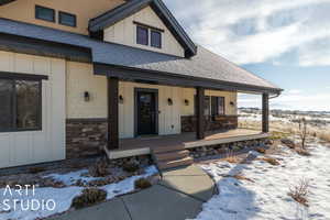 Snow covered property entrance with covered porch