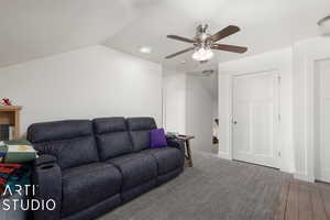 Living room featuring ceiling fan, lofted ceiling, and carpet floors