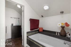 Bathroom with a relaxing tiled tub and lofted ceiling