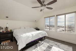 Bedroom with dark colored carpet, vaulted ceiling, and ceiling fan