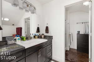 Bathroom with vanity, a shower with door, and lofted ceiling