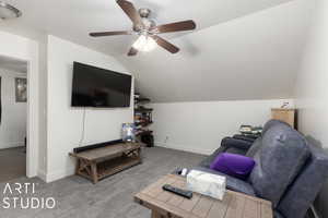 Carpeted living room with ceiling fan and lofted ceiling