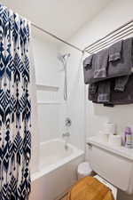 Bathroom with toilet and shower / tub combo with curtain