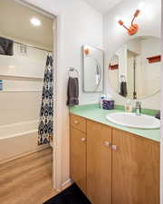 Bathroom featuring vanity, shower / bath combination with curtain, and hardwood / wood-style flooring