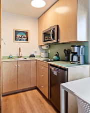 Kitchen with light brown cabinets, light wood-type flooring, stainless steel appliances, and sink