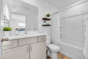 Full bathroom featuring shower / bath combination with curtain, toilet, wood-type flooring, and vanity