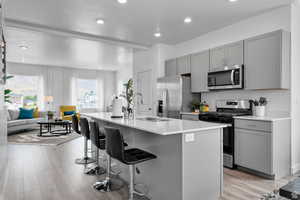 Kitchen with a center island with sink, sink, light wood-type flooring, and stainless steel appliances