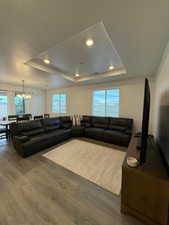 Living room featuring hardwood / wood-style floors, a textured ceiling, a tray ceiling, and a notable chandelier