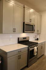 Kitchen featuring gray cabinetry, dark hardwood / wood-style flooring, and stainless steel appliances