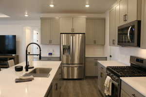 Kitchen with appliances with stainless steel finishes, dark hardwood / wood-style flooring, gray cabinetry, and sink