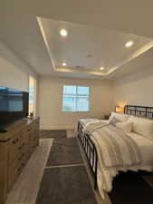 Carpeted bedroom with a tray ceiling and multiple windows