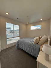 Bedroom with dark colored carpet and multiple windows