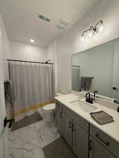 Bathroom featuring a textured ceiling, vanity, toilet, and curtained shower