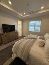 Bedroom featuring dark colored carpet, connected bathroom, and a raised ceiling