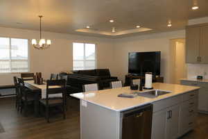 Kitchen featuring dishwasher, gray cabinets, a kitchen island with sink, and a healthy amount of sunlight