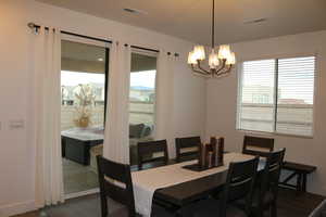 Dining room with dark hardwood / wood-style flooring and a notable chandelier