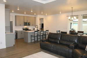 Living room featuring sink, dark wood-type flooring, and an inviting chandelier