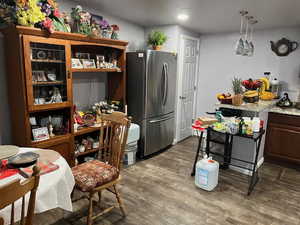 Kitchen with decorative light fixtures, dark hardwood / wood-style floors, stainless steel refrigerator, and light stone counters