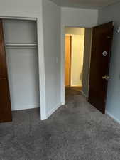 Unfurnished bedroom featuring dark carpet and a closet