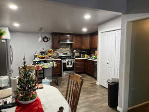 Kitchen featuring dark brown cabinetry, backsplash, stainless steel appliances, and hardwood / wood-style flooring