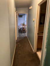 Hall with dark colored carpet, a textured ceiling, a wall mounted AC, and sink