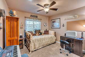 Carpeted bedroom with ceiling fan and a textured ceiling