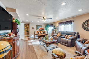 Living room featuring ceiling fan, light hardwood / wood-style floors, and a textured ceiling