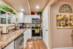 Kitchen featuring white cabinets, appliances with stainless steel finishes, light wood-type flooring, and sink