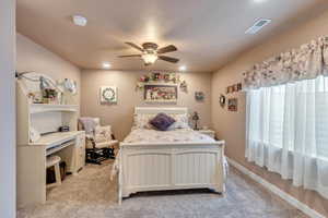 Carpeted bedroom featuring a textured ceiling and ceiling fan