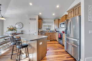 Kitchen with stainless steel appliances, hardwood / wood-style floors, a kitchen island, hanging light fixtures, and lofted ceiling