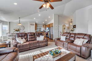 Living room with light hardwood / wood-style flooring, vaulted ceiling, and ceiling fan