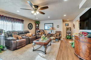 Living room featuring a textured ceiling, light wood-type flooring, and ceiling fan