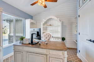 Office area with vaulted ceiling, ceiling fan, and wood walls