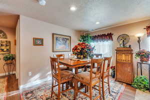 Dining space with light hardwood / wood-style floors and a textured ceiling