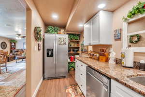 Kitchen featuring ceiling fan, light hardwood / wood-style floors, a textured ceiling, white cabinets, and appliances with stainless steel finishes