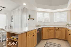 Kitchen featuring lofted ceiling, sink, black dishwasher, light tile patterned flooring, and kitchen peninsula