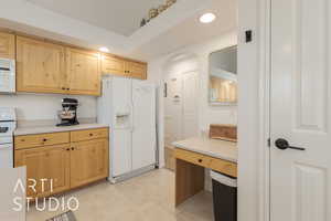 Kitchen with light brown cabinets and white appliances