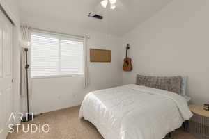 Carpeted bedroom with ceiling fan, a closet, and vaulted ceiling