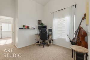 Carpeted home office with lofted ceiling