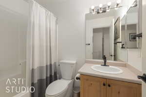 Bathroom featuring a shower with curtain, vanity, and toilet