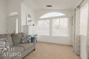 Carpeted living room featuring lofted ceiling