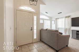 Tiled entrance foyer with vaulted ceiling and an inviting chandelier