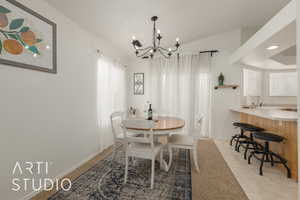 Tiled dining room with sink, vaulted ceiling, a healthy amount of sunlight, and a notable chandelier