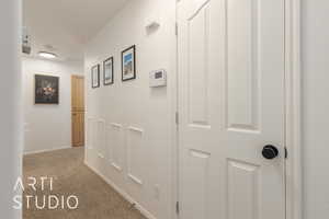 Corridor featuring light colored carpet