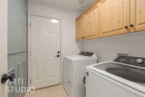 Laundry room with cabinets, washing machine and dryer, and light tile patterned flooring